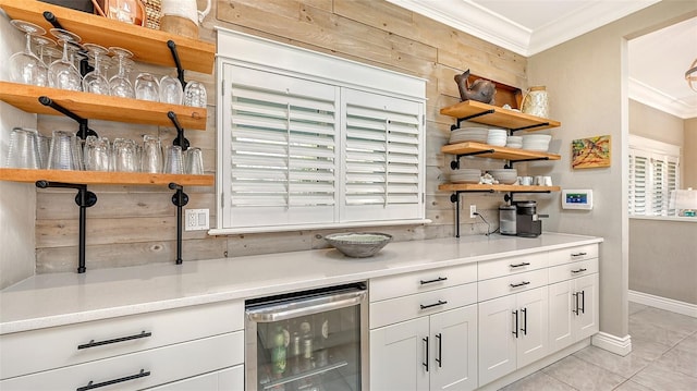 kitchen with ornamental molding, light tile patterned floors, white cabinets, wine cooler, and plenty of natural light