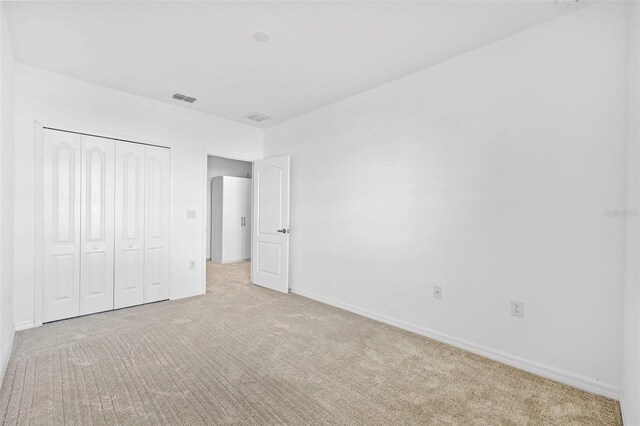 unfurnished bedroom featuring a closet and light colored carpet