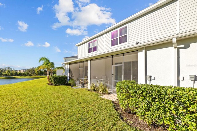 rear view of house featuring a sunroom, a yard, and a water view