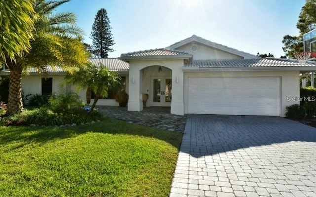 mediterranean / spanish home featuring french doors, a front lawn, and a garage