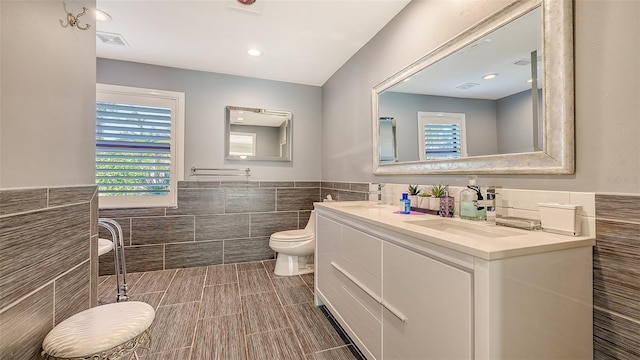 bathroom with vanity, tile walls, and toilet