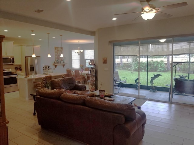 living room with light tile patterned floors and ceiling fan with notable chandelier