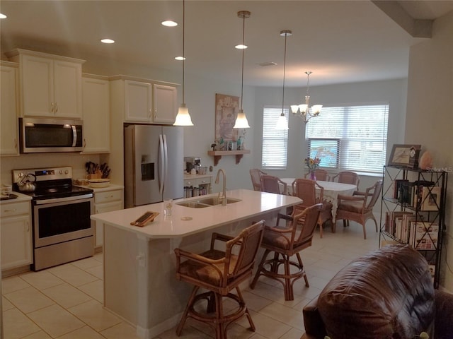 kitchen featuring a center island with sink, decorative light fixtures, sink, and stainless steel appliances