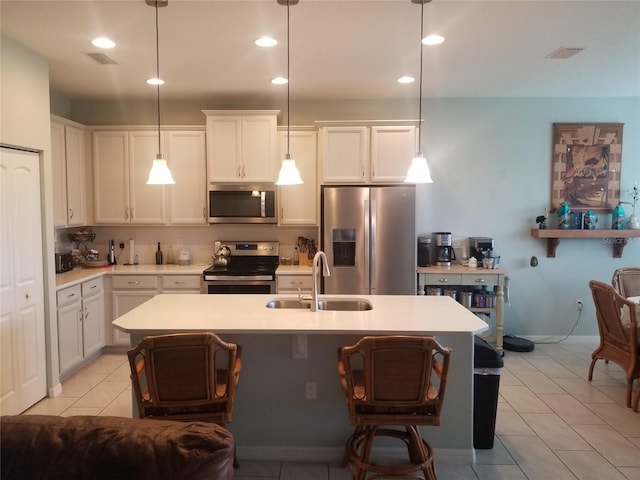 kitchen with white cabinetry, sink, an island with sink, decorative light fixtures, and appliances with stainless steel finishes