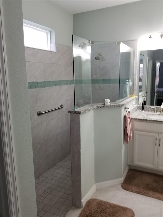 bathroom featuring tiled shower, vanity, and tile patterned flooring