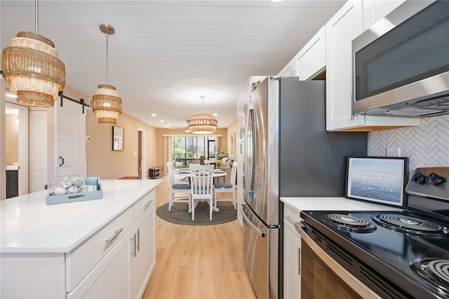 kitchen featuring white cabinets, decorative light fixtures, tasteful backsplash, range with electric cooktop, and a barn door