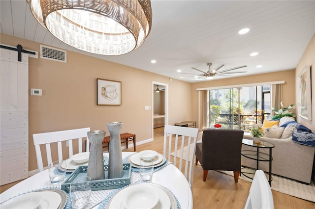 dining room featuring wood ceiling, ceiling fan, a barn door, and light hardwood / wood-style floors