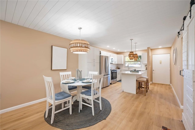 dining room with light hardwood / wood-style floors, wood ceiling, and a barn door