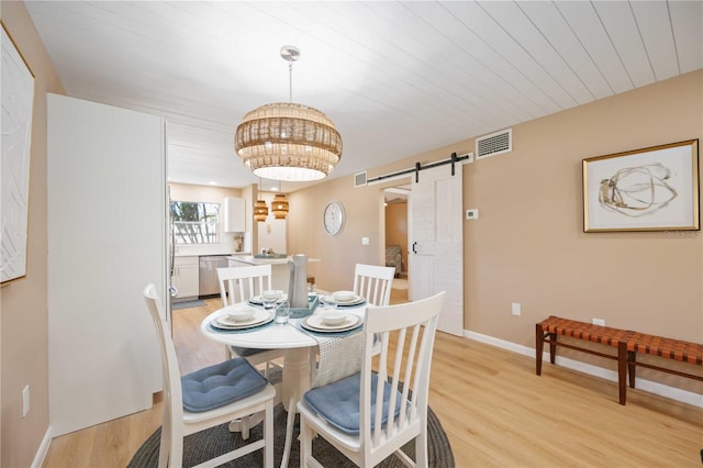 dining area with light hardwood / wood-style flooring and a barn door