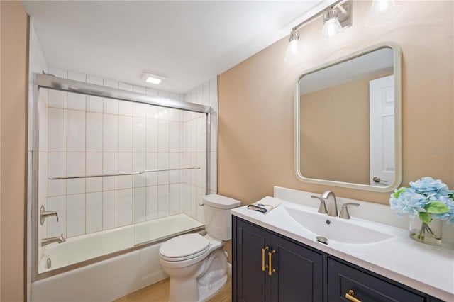 full bathroom with wood-type flooring, bath / shower combo with glass door, toilet, and vanity