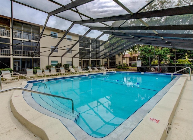 view of pool with glass enclosure and a patio area