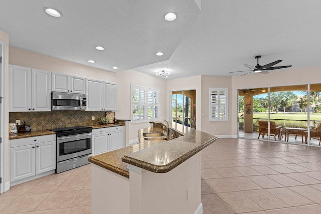 kitchen featuring white cabinetry, sink, backsplash, a center island with sink, and appliances with stainless steel finishes