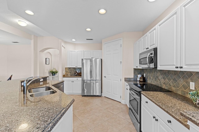 kitchen with decorative backsplash, stainless steel appliances, sink, light tile patterned floors, and white cabinets