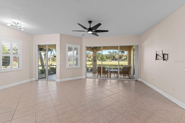 spare room with ceiling fan, light tile patterned flooring, and a textured ceiling