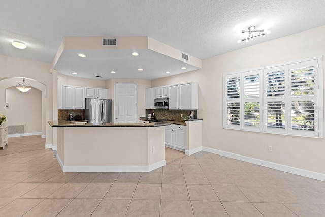 kitchen with white cabinets, light tile patterned floors, tasteful backsplash, a kitchen island, and stainless steel appliances