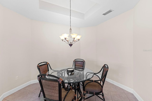 tiled dining room featuring a chandelier and a raised ceiling