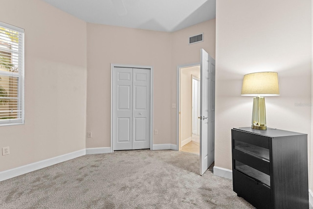 unfurnished bedroom with light colored carpet and a closet