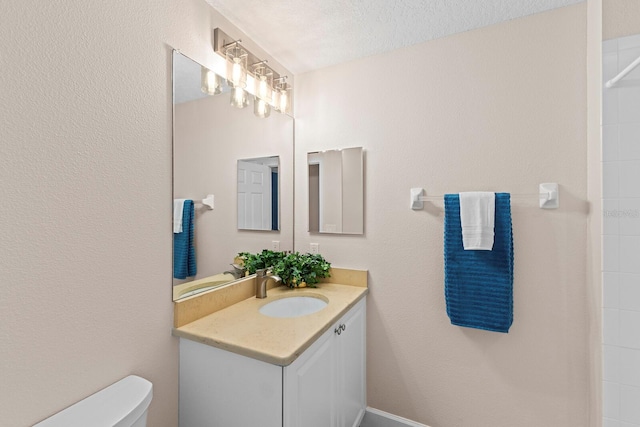 bathroom featuring vanity, toilet, and a textured ceiling