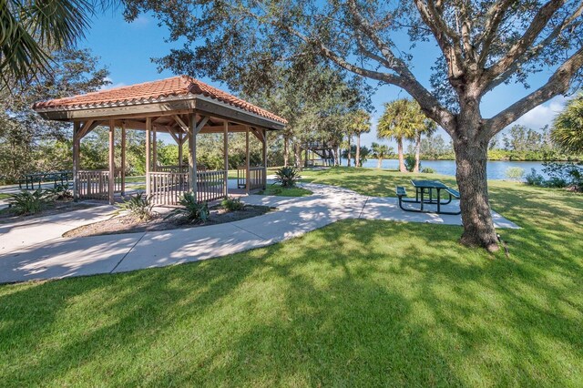 view of property's community with a gazebo, a water view, and a lawn