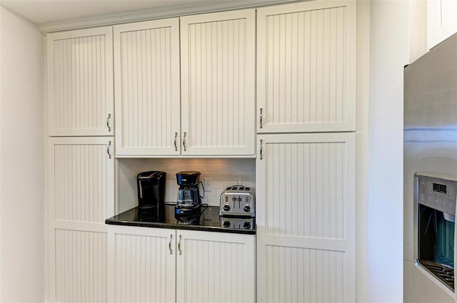 kitchen with white cabinetry, backsplash, and dark stone counters