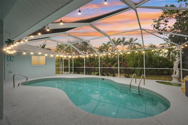 pool at dusk featuring glass enclosure and a patio area