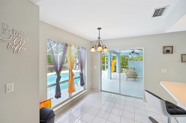 doorway to outside with plenty of natural light, light tile patterned floors, and an inviting chandelier