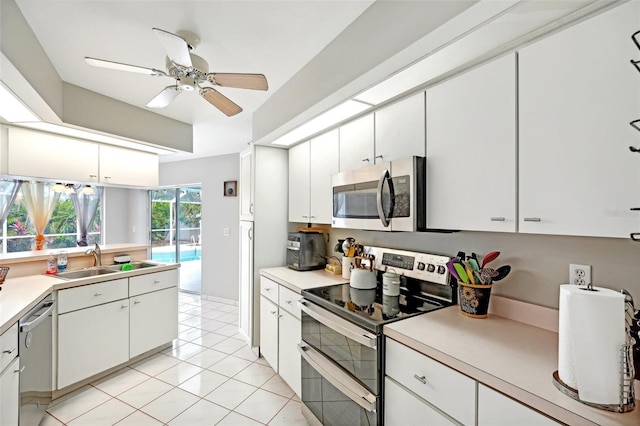 kitchen with appliances with stainless steel finishes, ceiling fan, sink, light tile patterned floors, and white cabinetry