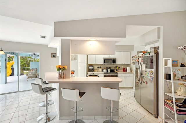 kitchen featuring a breakfast bar area, white cabinetry, light tile patterned floors, and stainless steel appliances