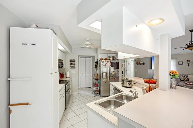 kitchen with black electric range oven, sink, stainless steel fridge, white fridge, and white cabinetry