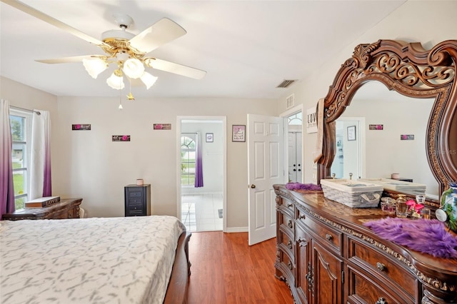 bedroom featuring multiple windows, light hardwood / wood-style floors, and ceiling fan