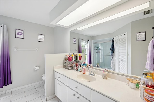 bathroom with tile patterned floors, a shower with door, vanity, and toilet