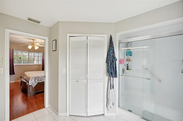 bathroom with hardwood / wood-style flooring, a shower with door, and ceiling fan