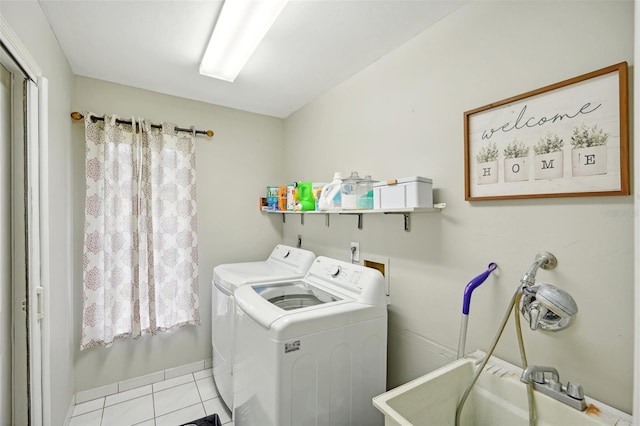 laundry area with light tile patterned floors, washer and clothes dryer, and sink