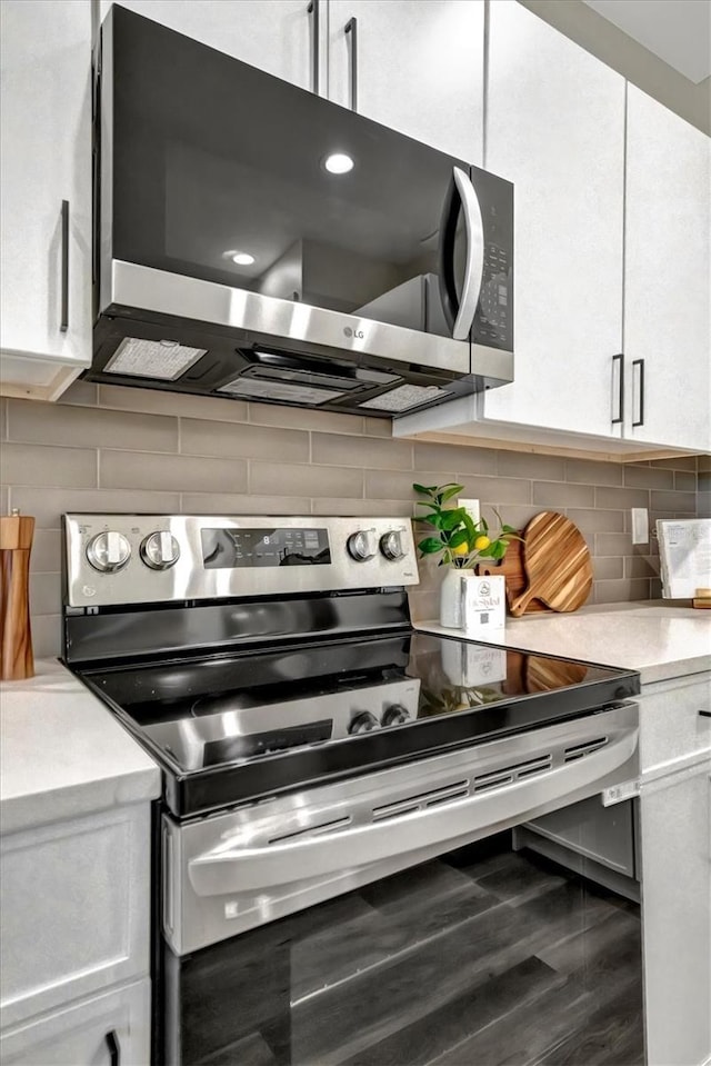 kitchen with hardwood / wood-style floors, white cabinetry, backsplash, and appliances with stainless steel finishes