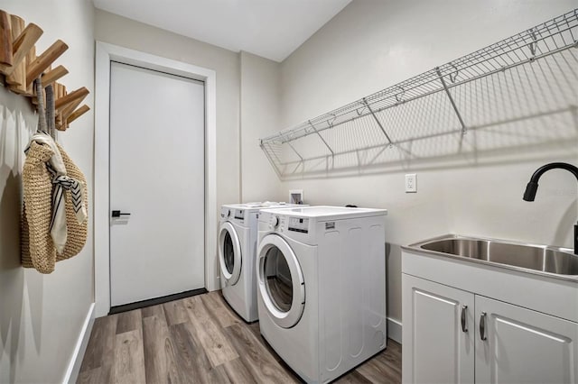 laundry room with cabinets, hardwood / wood-style floors, washing machine and dryer, and sink