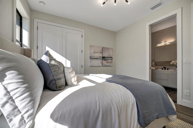 bedroom with dark hardwood / wood-style flooring, connected bathroom, and a closet