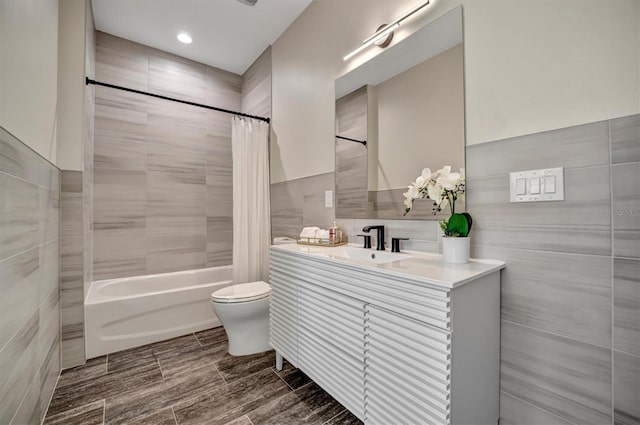 full bathroom featuring vanity, shower / bathtub combination with curtain, toilet, and tile walls