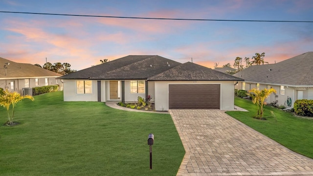 single story home with a lawn, cooling unit, and a garage