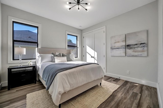 bedroom with an inviting chandelier, dark wood-type flooring, and multiple windows