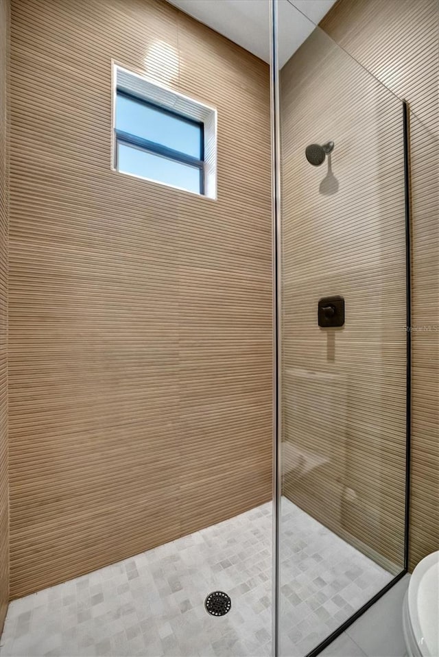 bathroom featuring tiled shower and toilet