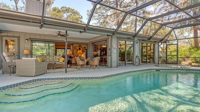 view of pool featuring outdoor lounge area, glass enclosure, ceiling fan, and a patio area