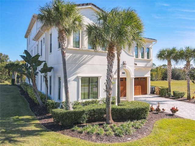 mediterranean / spanish-style home with a garage and a front lawn