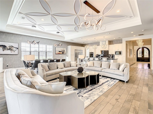 living room with a chandelier, a tray ceiling, and light hardwood / wood-style flooring