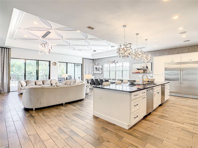 kitchen featuring sink, hanging light fixtures, light hardwood / wood-style flooring, white cabinetry, and stainless steel appliances