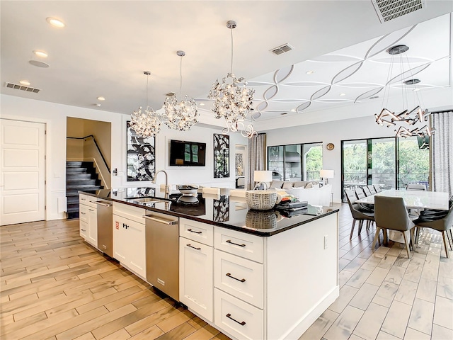 kitchen with white cabinets, sink, decorative light fixtures, and an island with sink