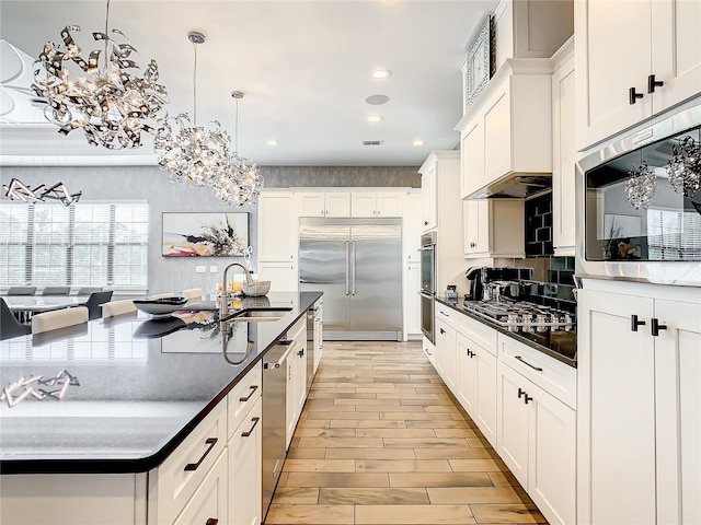 kitchen with pendant lighting, stainless steel appliances, white cabinetry, and sink