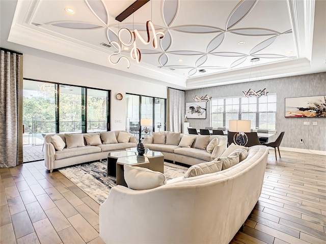 living room with wood-type flooring, a tray ceiling, and an inviting chandelier