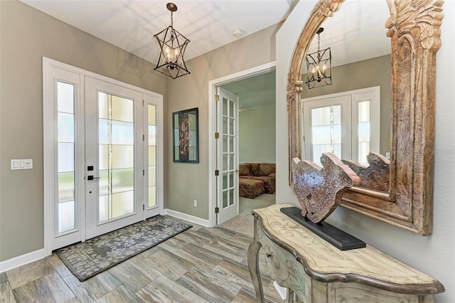 foyer featuring hardwood / wood-style floors, a chandelier, a healthy amount of sunlight, and french doors