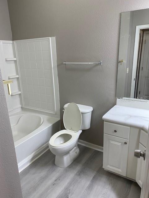 full bathroom with hardwood / wood-style flooring, vanity, toilet, and bathing tub / shower combination