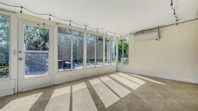 unfurnished sunroom featuring a wall unit AC and track lighting